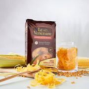 One packet of Le Veneziane Gluten Free Pasta Fettuccine Nests, pictured with corn in background and pasta nest in front.